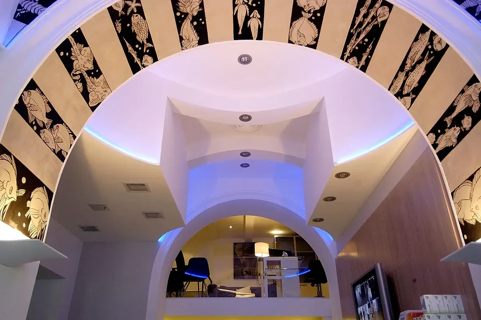 Sculptural ceiling with curved volumes and coloured lighting