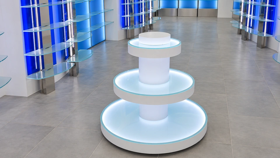 Backlit circular display island with glass shelves and blue shelving