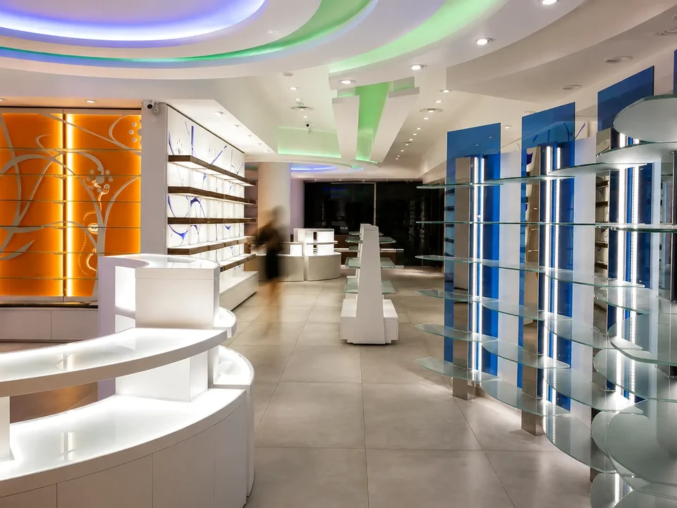 Route between white shelving and backlit walls