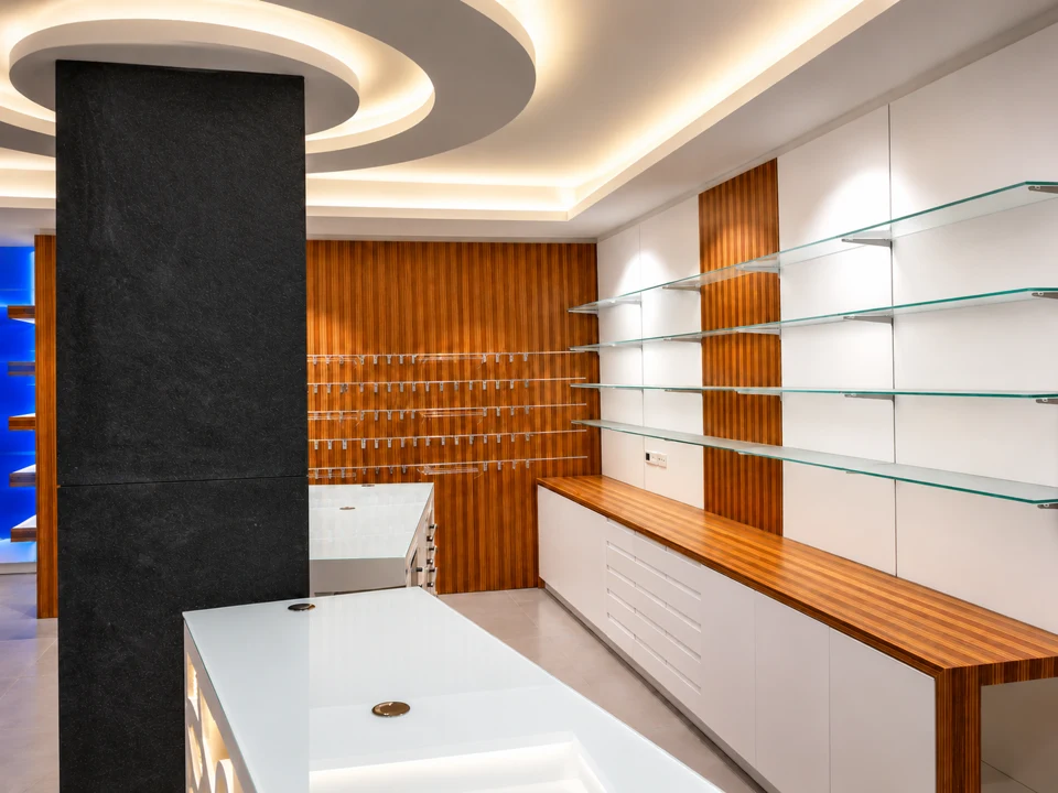 Curves and light: interwoven wood — Wood and glass back counter around a dark pillar
